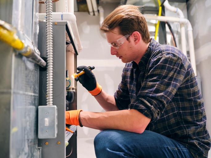 Technician inspecting and repairing an HVAC furnace system in Hunterdon County, NJ