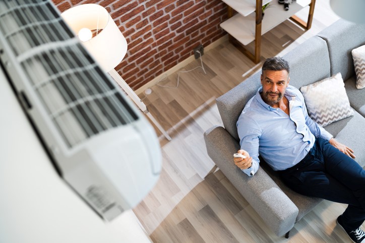 A man using a remote to control a wall-mounted air conditioner in Hunterdon County, NJ